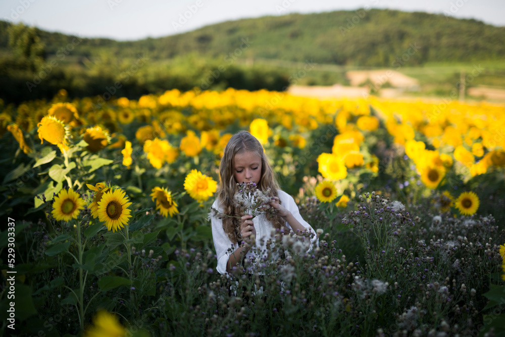 Teenage girl holding flowers on sunflower field Teenage girl holding flowers on sunflower field