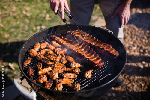 Low section of man grilling meat on barbecue photo