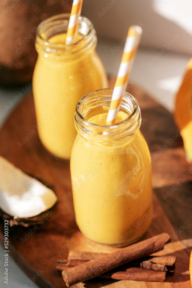 Pumpkin and coconut smoothie with cinnamon in bottles with straw. Healthy raw vegan food. Closeup Pumpkin and coconut smoothie with cinnamon in bottles with straw. Healthy raw vegan food. Closeup