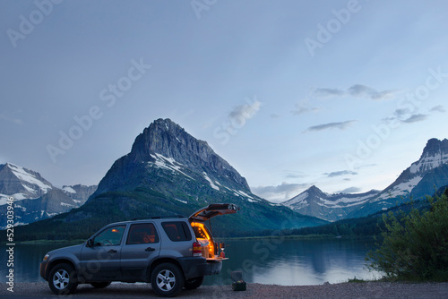 Sports utility vehicle parked on shore of Swiftcurrent lake against Mt. Grinnell photo