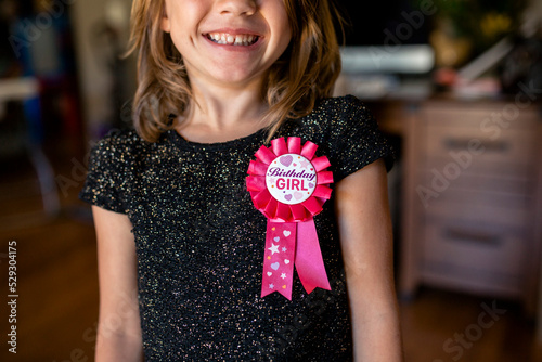 Midsection of happy girl with birthday badge at home photo