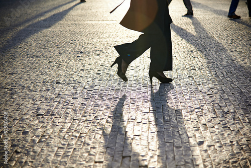 Low section of businesswoman walking on cobbled footpath