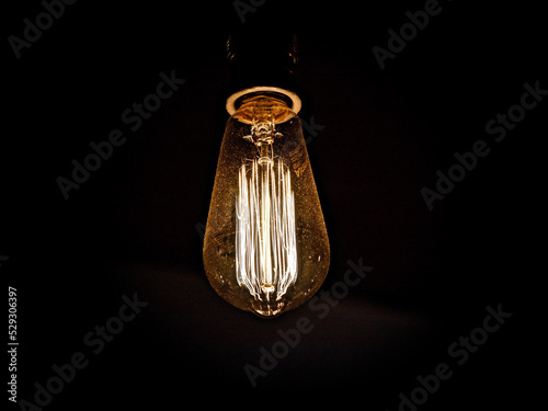 Close-up of illuminated light bulb hanging in darkroom
