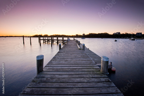 Wooden pier over sea against clear sky during sunrise photo