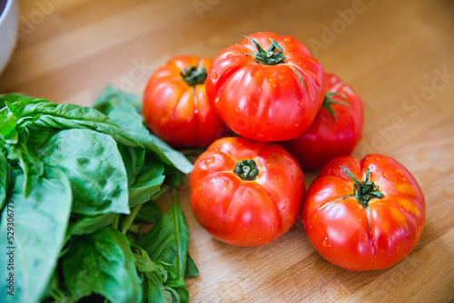 High angle view of wet tomatoes with basils on wooden table in kitchen photo