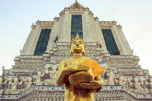 Low angle view of Buddha statue by Wat Arun temple against sky