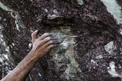 Cropped chalky hand of man gripping on rocks during mountain climbing photo