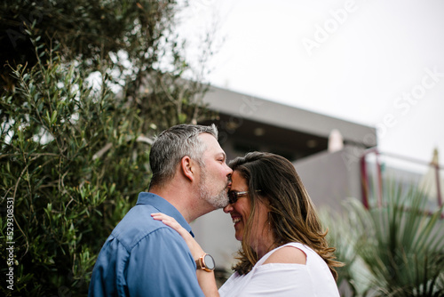 Romantic husband kissing wife while standing at tourist resort against clear sky photo