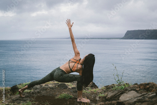 Rear view of woman practicing yoga at beach against cloudscape photo