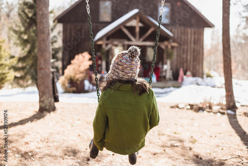 Rear view of girl sitting on swing at playground during winter photo