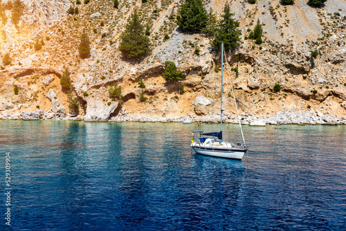 Saint George bay on Symi island, popular stop over for tourists to have a swim in the turquoise waters, Symi island, Greece. Boat sailing at the Symi island and part of the Dodecanese island group. © daliu