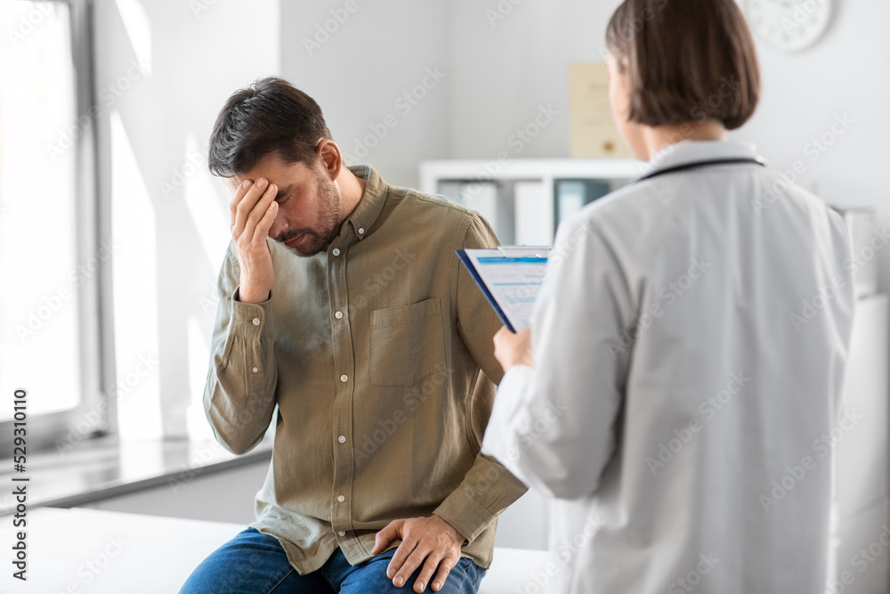 Obraz premium medicine, healthcare and people concept - female doctor with clipboard and sad male patient having health problem at hospital