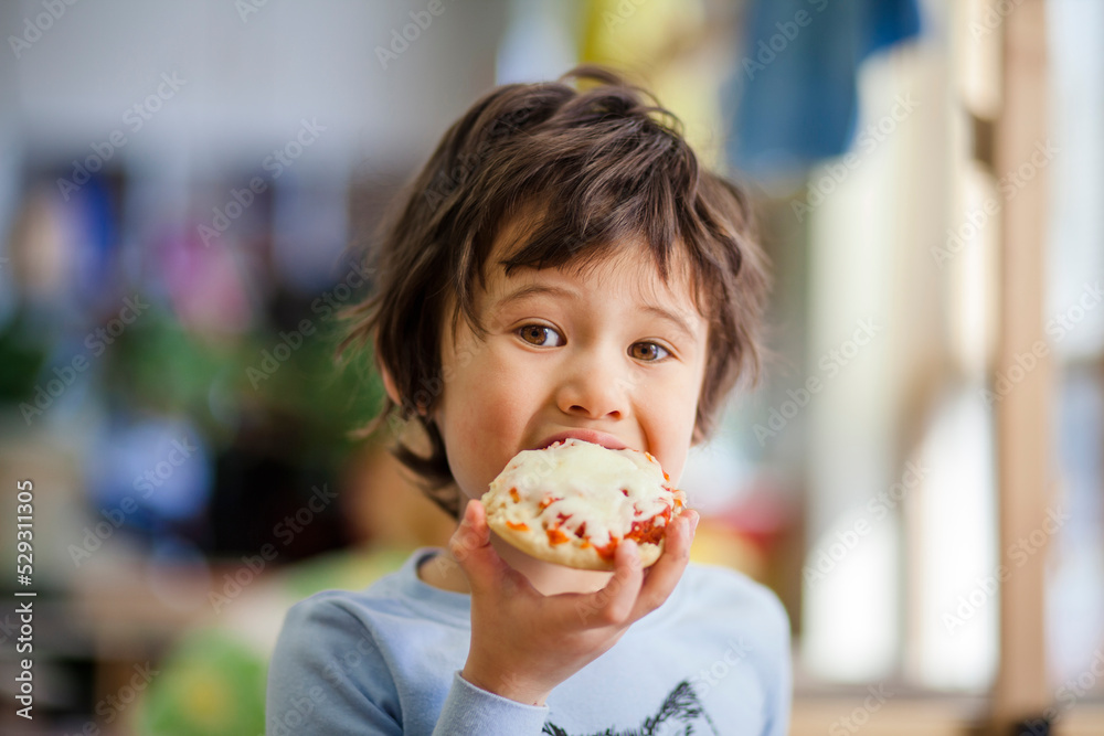 Portrait of boy eating pizza muffin in cafe Portrait of boy eating pizza muffin in cafe