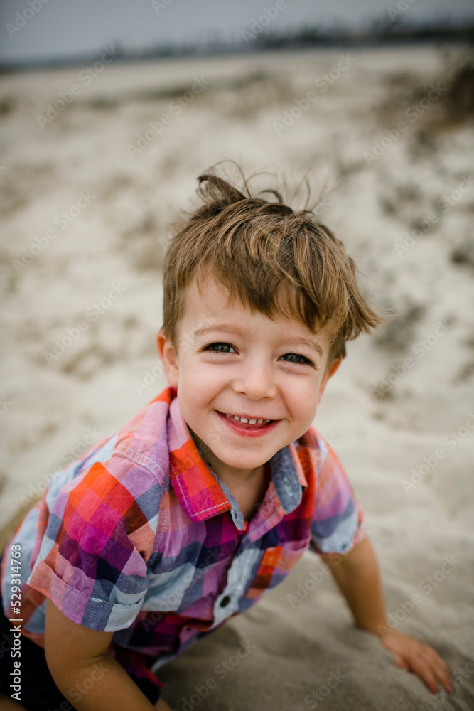 Portrait of happy cute boy sitting on sand at beach Portrait of happy cute boy sitting on sand at beach
