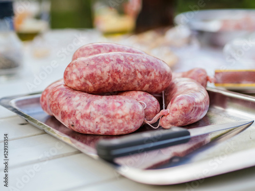 Close-up of sausages with knife in plate on wooden table at yard photo