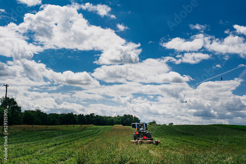 Tractor on agricultural landscape against cloudy sky