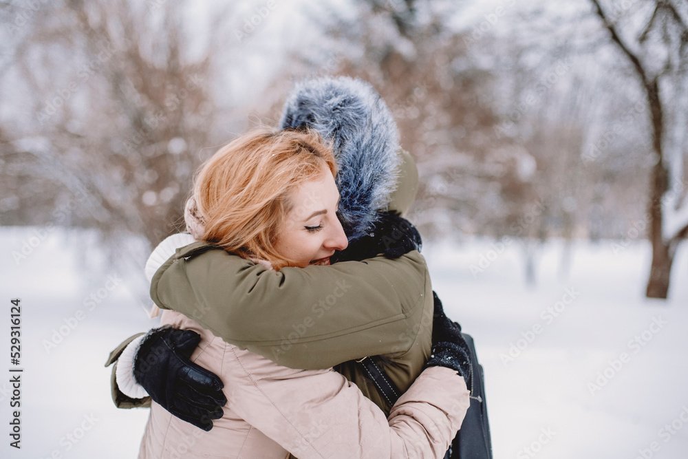 Side view of happy lesbian couple embracing while standing in park during winter Side view of happy lesbian couple embracing while standing in park during winter