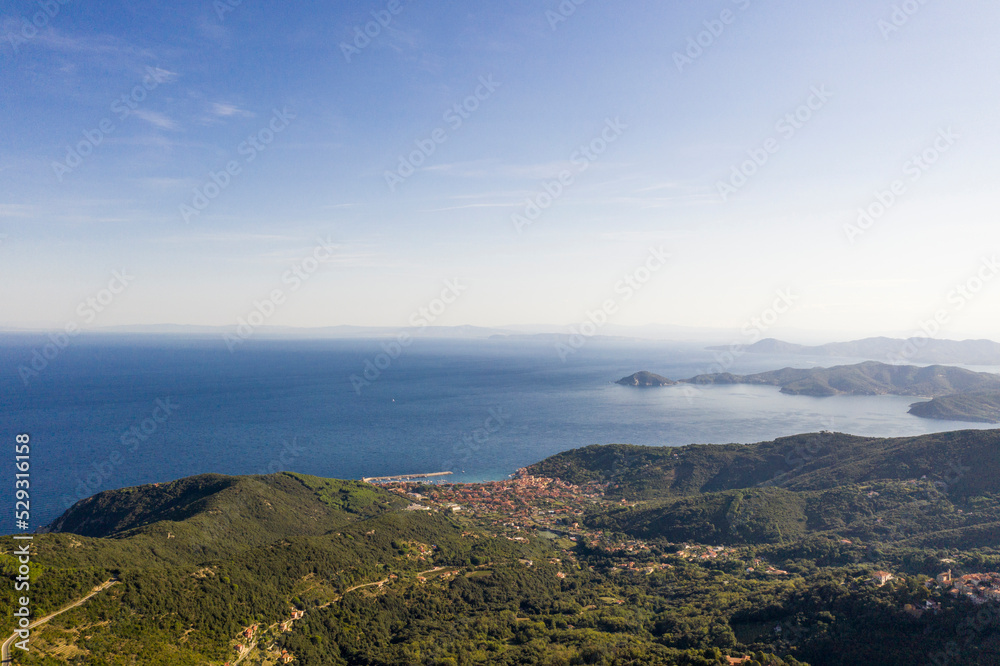 Aerial view of mountains by sea against sky during sunny day Aerial view of mountains by sea against sky during sunny day