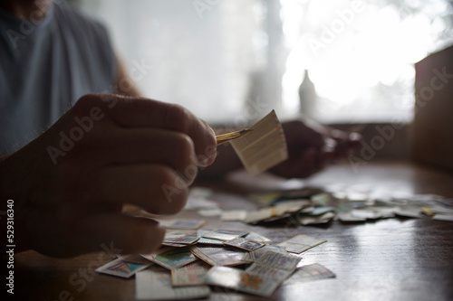 Close-up of man holding postage stamps with tweezers on table at home