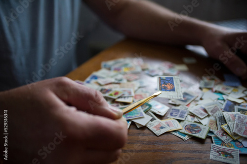 Midsection of man holding postage stamp with tweezers on table at home photo