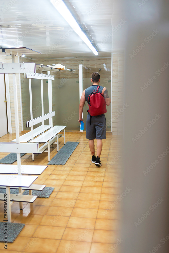 Rear view of man with backpack walking in gym Rear view of man with backpack walking in gym