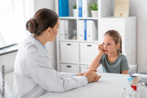 medicine  healthcare and pediatry concept - female doctor or pediatrician talking to little girl patient on medical exam at clinic
