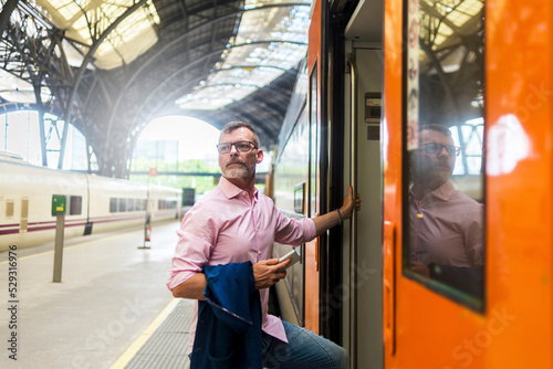 Businessman looking away while entering in train at railroad station platform