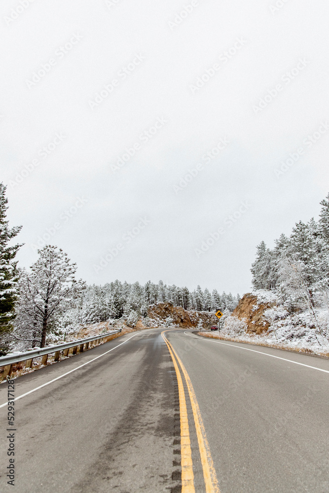 Diminishing perspective of empty road amidst snow covered trees against sky in forest Diminishing perspective of empty road amidst snow covered trees against sky in forest