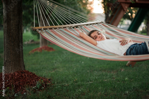 Portrait of girl with hand behind head lying on hammock at park photo
