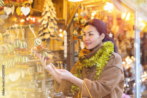 Positive female in tinsel on Christmas fair decoration on holiday