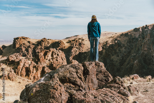 Woman standing on rock overlooking a canyon photo