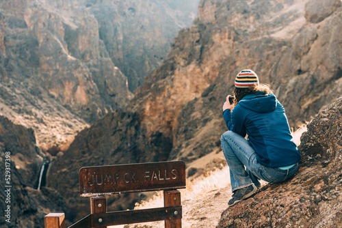 Woman taking a picture of a waterfall in the distance photo