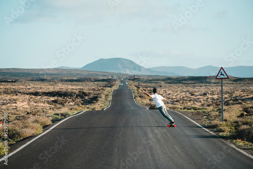 Full length of young man skateboarding on country road against sky photo