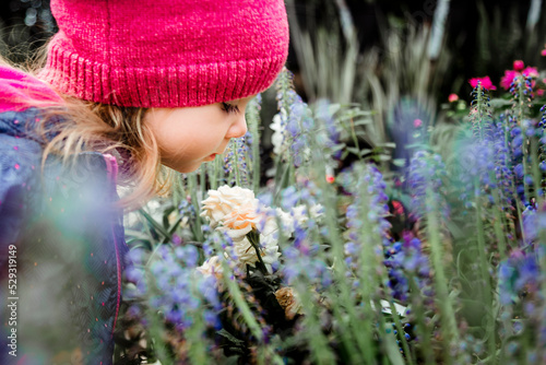 young toddler girl smelling flowers at a garden center
