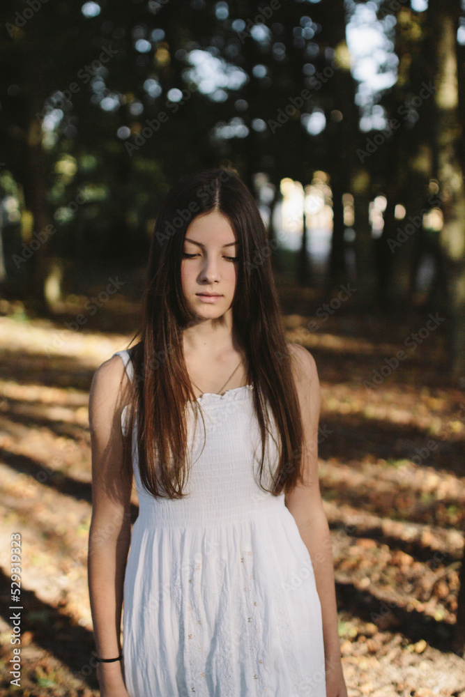 Brunette woman walks through the woods in a white dress Brunette woman walks through the woods in a white dress