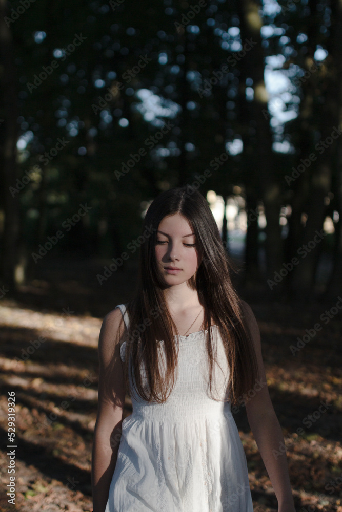 Brunette woman walks through the woods in a white dress Brunette woman walks through the woods in a white dress