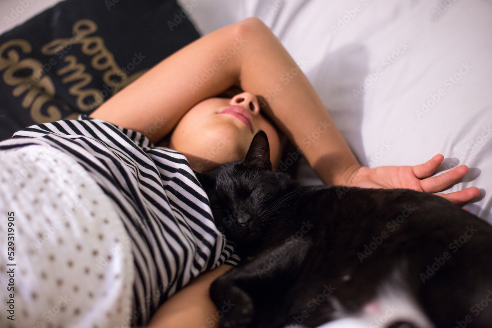 Black cat snuggles up and sleeps next to sleeping girl Black cat snuggles up and sleeps next to sleeping girl