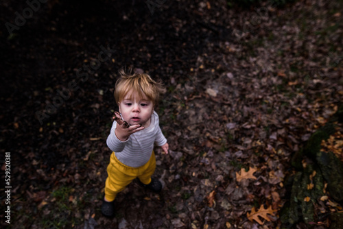 young boy holds up muddy hand while looking at it with distress photo