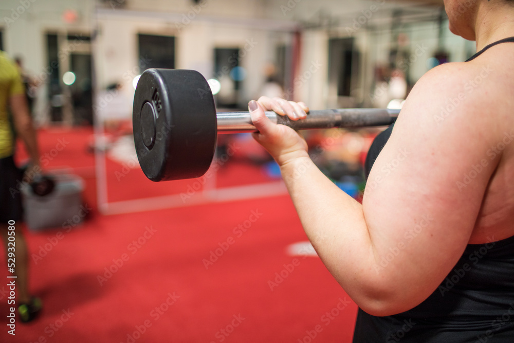 Detail of strong woman training biceps with curls at the gym. Detail of strong woman training biceps with curls at the gym.