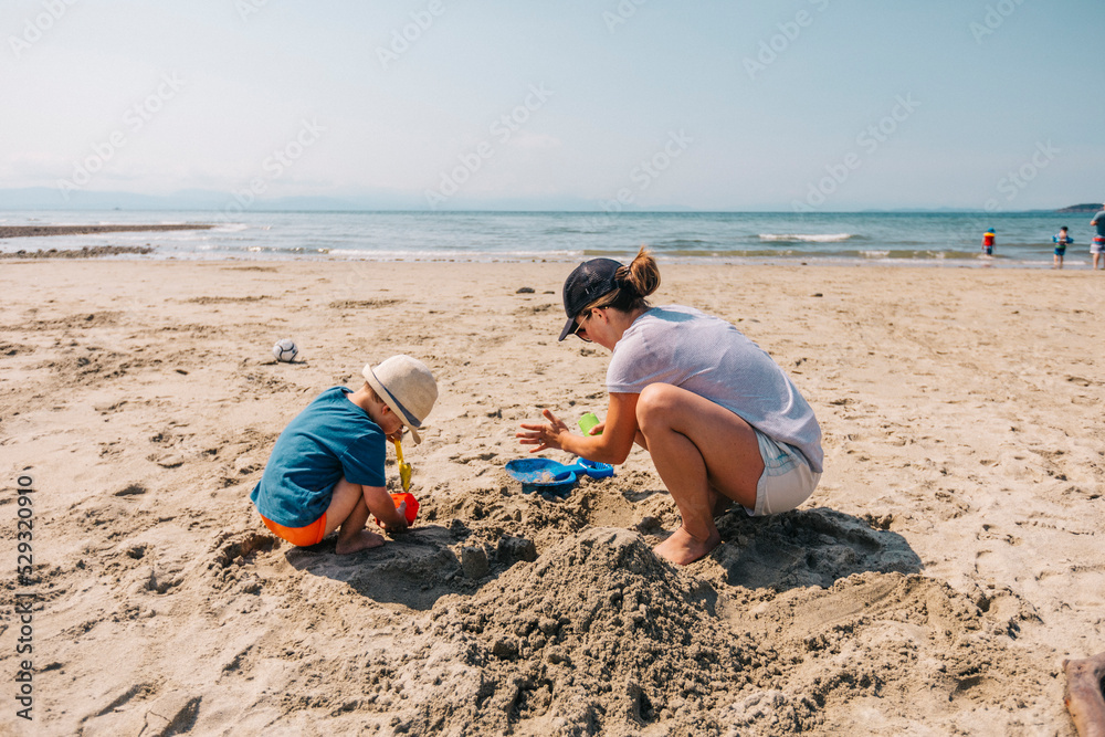 Mother playing in the sand with her son at the beach. Mother playing in the sand with her son at the beach.
