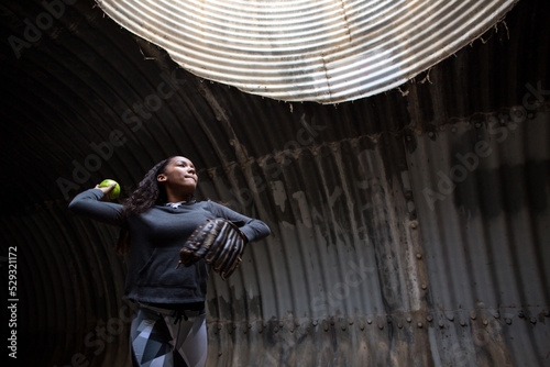 Girl in a tunnel in mid throw of a softball