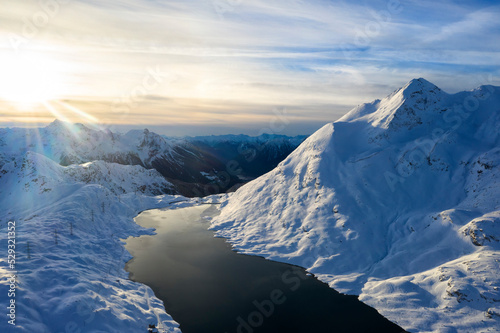 Sunburst on snowy peaks and frozen Lago Bianco, Switzerland photo
