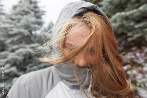 Portrait of a young blonde woman outdoors with hair covering face photo