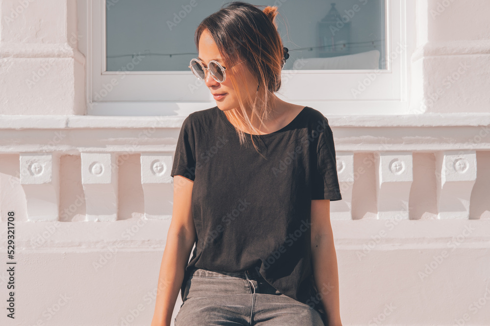 Asian woman wearing sunglasses on a sunny day with jeans and a t-shirt Asian woman wearing sunglasses on a sunny day with jeans and a t-shirt