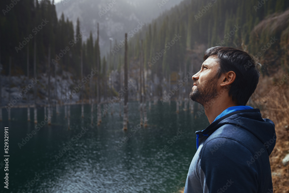 Man exploring the mountain lake with submerged trees Man exploring the mountain lake with submerged trees