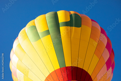 A hot air balloon ascends under a clear blue sky