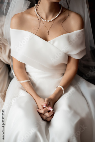 young girl in a white wedding dress keeps her hands clasped