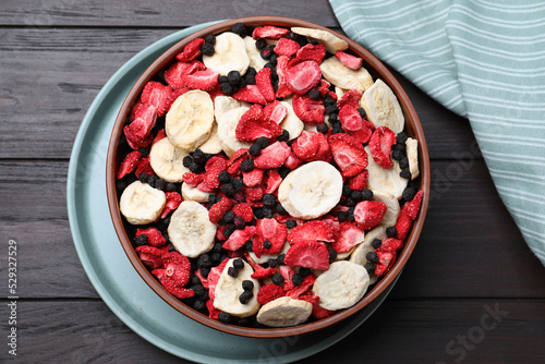 Bowl of different freeze dried fruits on wooden table, top view photo