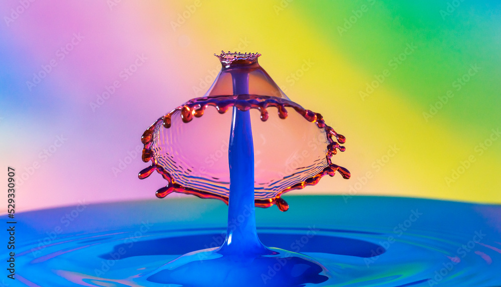 Water drop collision a beautiful cone shape hat on the top of a blue spike in colorful background Water drop collision a beautiful cone shape hat on the top of a blue spike in colorful background