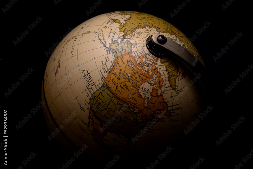 Moody picture of antique spinning globe model surrounded by darkness concept for menacing shadows covering the world, worldwide worry about the future of planet earth and global conflict